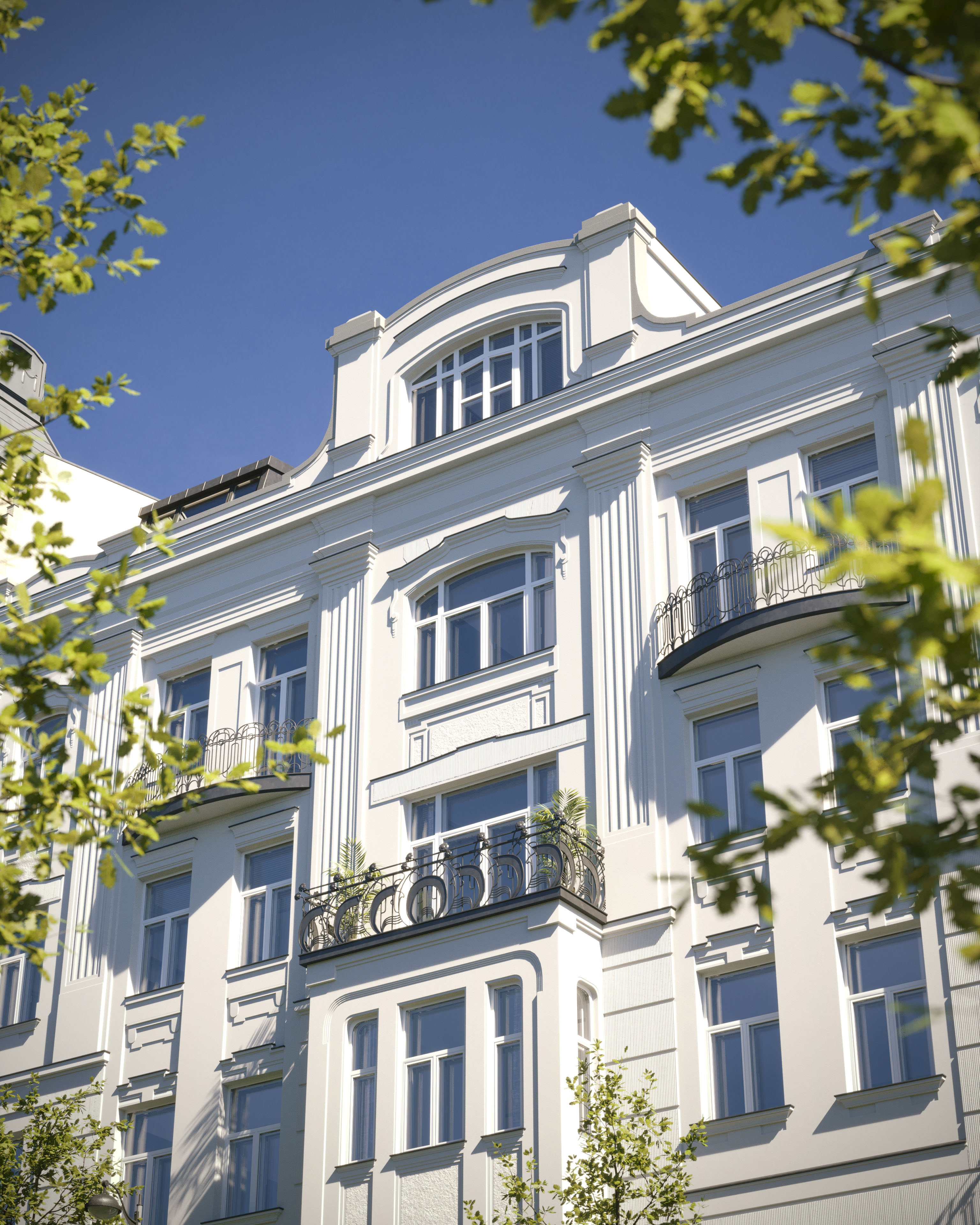 Looking up at the restored Secession façade of Alkotmány 27 through summer foliage, 3D rendering