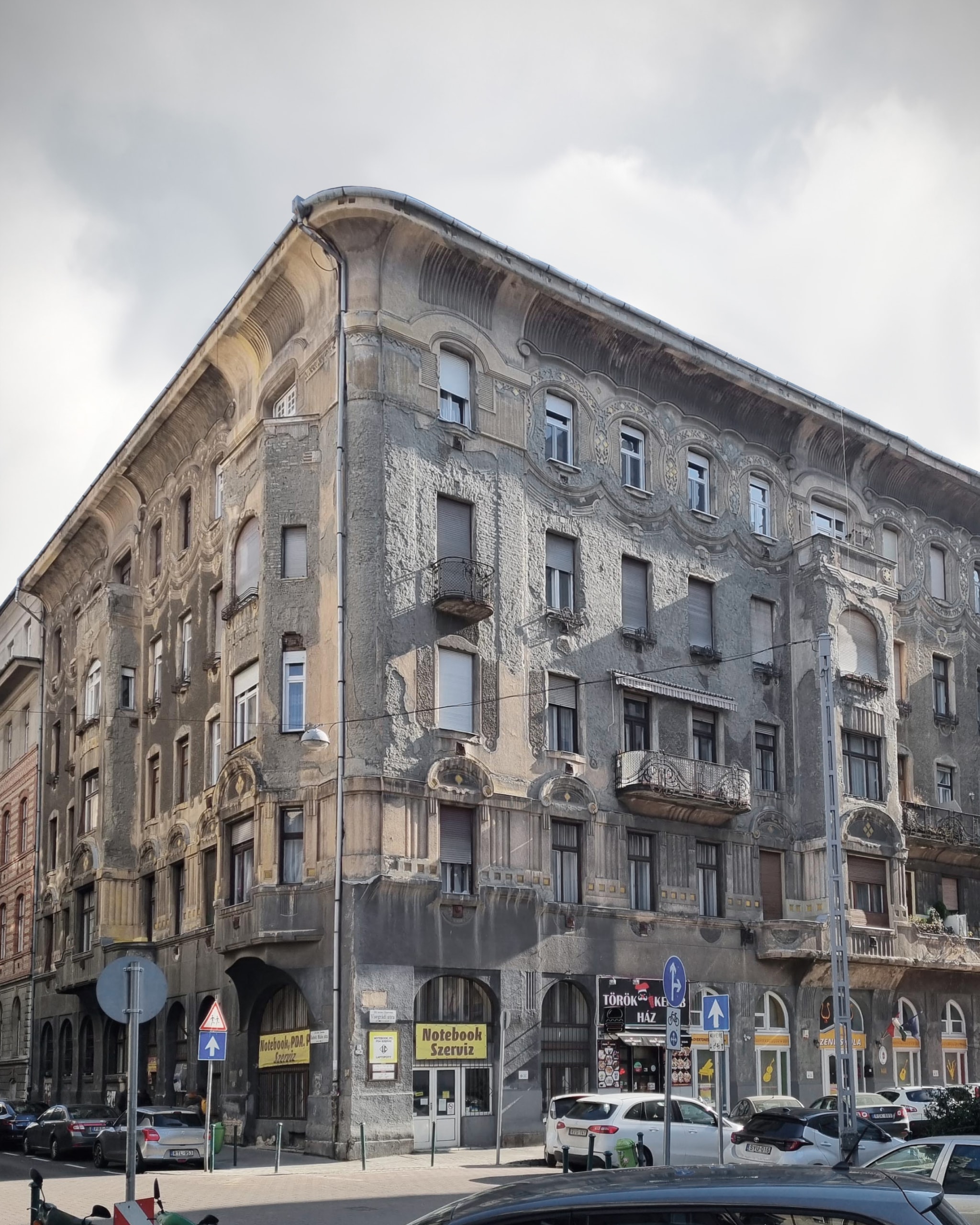 Current state of Visegrádi 17 in Budapest, the stained corner façade with shop signs, photo